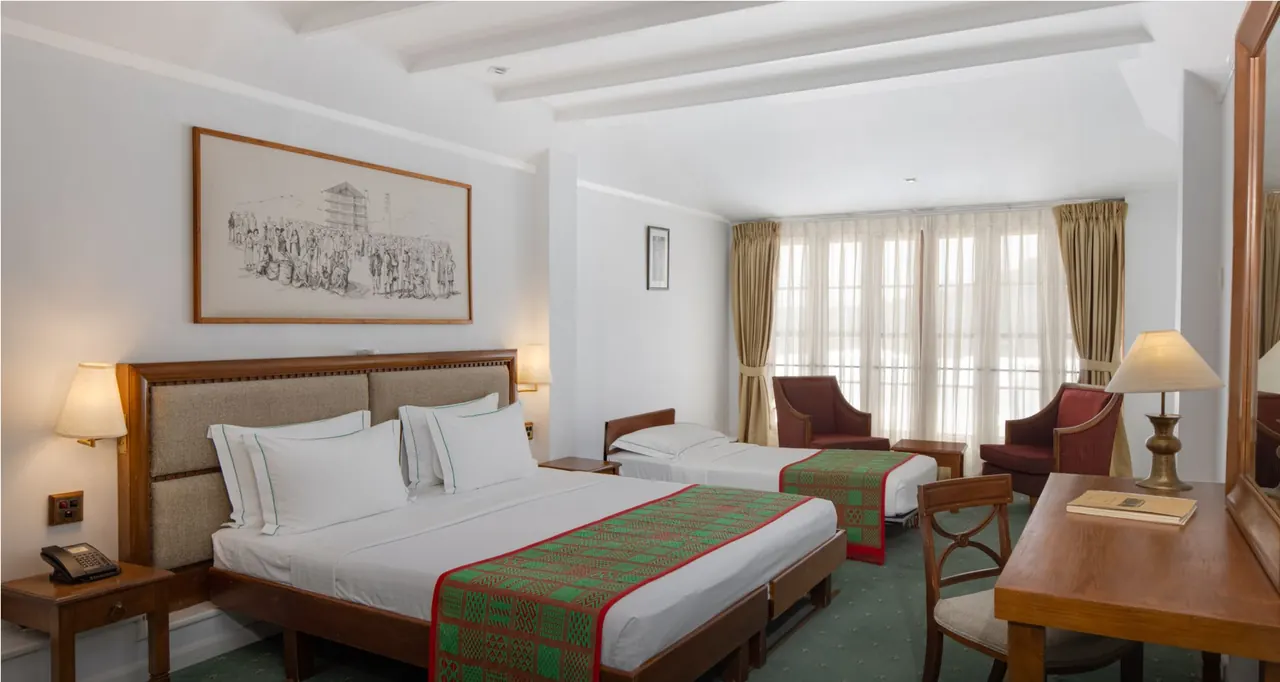 Bed and window in a Heritance Tea Factory Superior room